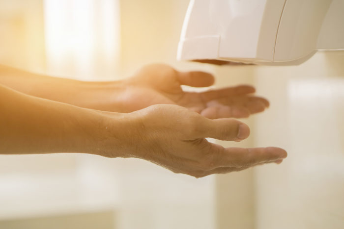 Handen drogen met een droogmachine in plaats van meer kiemen verspreiden